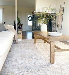 a living room with a couch, coffee table and fire place in the center area