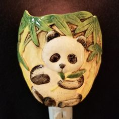 a ceramic panda bear sitting on top of a light switch cover with bamboo leaves around it