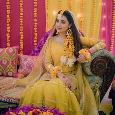 a woman sitting on top of a couch wearing a yellow dress and flowers in her hair