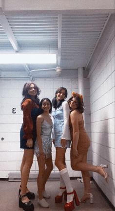 four women in short dresses and high heeled shoes posing for the camera