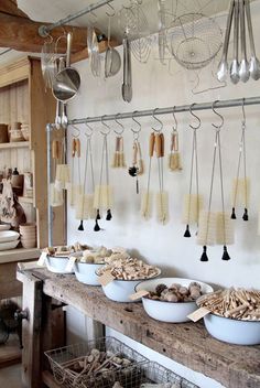 several bowls and spoons on a table in a room with hanging utensils