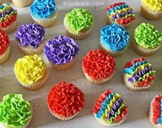 cupcakes decorated with rainbow icing on a table