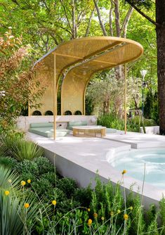 a gazebo in the middle of a lush green park with yellow flowers and trees