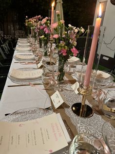 a long table set with place settings and candles