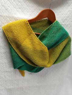 a green and yellow scarf hanging on a wooden hanger