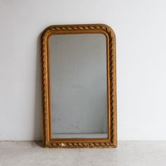 an old gold framed mirror against a white wall