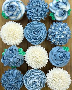 cupcakes decorated with blue and white flowers on a wooden table in the shape of roses