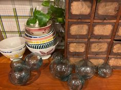 some glass balls are sitting on a table next to a stack of drawers and bowls