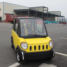 a small yellow and black car parked in a parking lot next to an industrial building