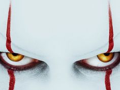 an evil looking face with yellow eyes and red blood on the side of its eye