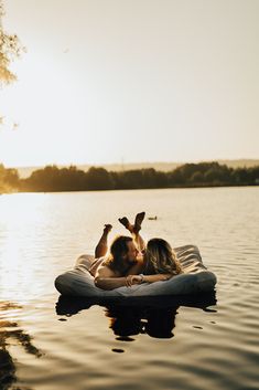 two women are laying on an inflatable floating bed while the sun is setting