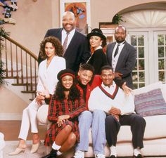 a group of people sitting on top of a white couch in a living room next to a staircase