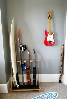 a surfboard and guitar hang on the wall next to a rack with two guitars