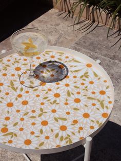 an orange and white flowered table with a drink on it