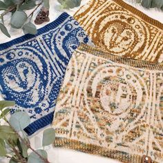 three different colored rugs sitting on top of a white table next to green leaves