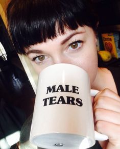 a close up of a person holding a coffee cup with the words male tears on it