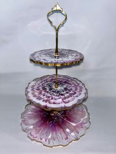 three tiered serving tray with pink and purple flowers on each side, holding a gold handle