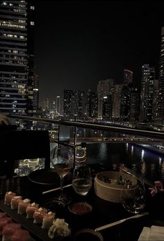 a table topped with sushi and chopsticks in front of a cityscape