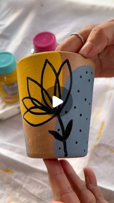 a person holding up a cup with a flower painted on the outside and inside it