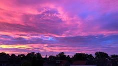 pink and purple clouds in the sky above houses