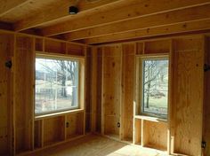 an empty room with three windows and no insulation in the wall, along with wood paneling on the walls