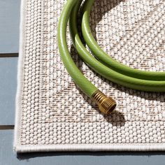 two green hoses sitting on top of a table next to a white cloth and wooden floor