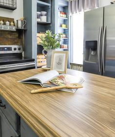 an open book sitting on top of a wooden counter next to a refrigerator freezer