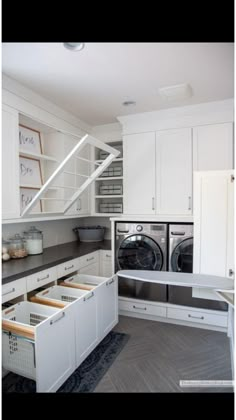 a washer and dryer in a room with white cupboards, drawers and shelves