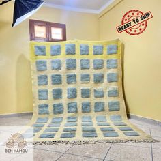 a blue and yellow blanket sitting on top of a tiled floor next to a window