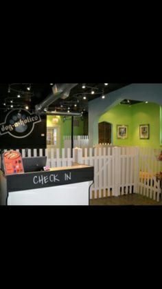 the check in desk is next to a white picket fence and green walls with pictures on it