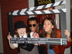 three people posing for a photo in front of a movie clapper frame with the words seme clara's birthday cinema written on it