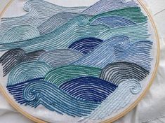 a close up of a embroidery on a piece of cloth with waves in the background