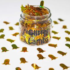 a jar filled with glitter lambs sitting on top of a white table covered in confetti