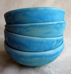 four blue bowls stacked on top of each other in front of a white tablecloth