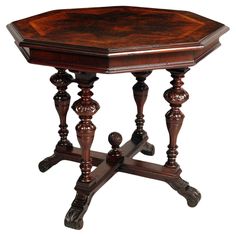 an octagonal wooden table with turned legs and carved wood decoration on the top, sitting upright against a white background