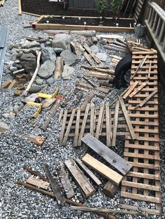 a pile of wood sitting on top of a gravel covered ground