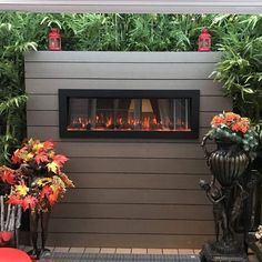 a fire place in the middle of a patio surrounded by plants and flowers on either side