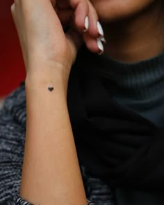 a woman with a small heart tattoo on her wrist