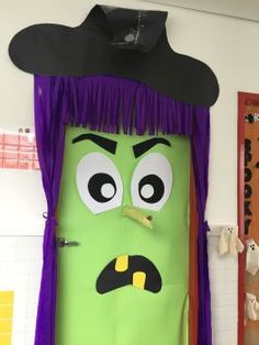 a door decorated to look like a green monster with purple hair and eyes wearing a witches hat