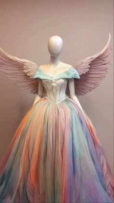 a mannequin dressed in a multicolored dress with large wings on display