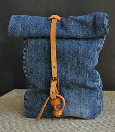 a pair of blue jeans with a brown leather strap sitting on top of each other