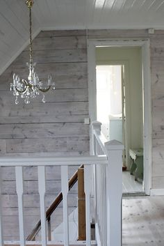 an empty room with white walls and wood flooring, chandelier hanging from the ceiling