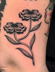 a black and white flower tattoo on the back of a woman's left leg