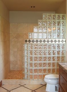 a bathroom with a toilet, sink and glass block wall in the shower stall area