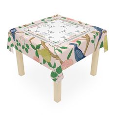 a table cloth with birds and flowers on it, sitting on top of wooden legs