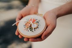 a close up of a person holding a small embroidered item in their hands with flowers on it