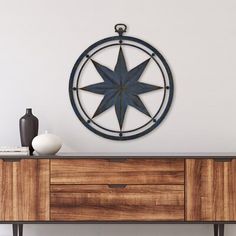 a wooden cabinet with a metal star on it and a vase sitting on top of it