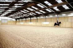 a person riding on the back of a horse in an indoor arena with wooden walls