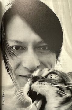 a black and white photo of a woman holding a cat up to her face while smiling