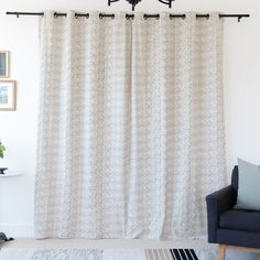 a living room with a couch, chair and curtain in front of a white wall